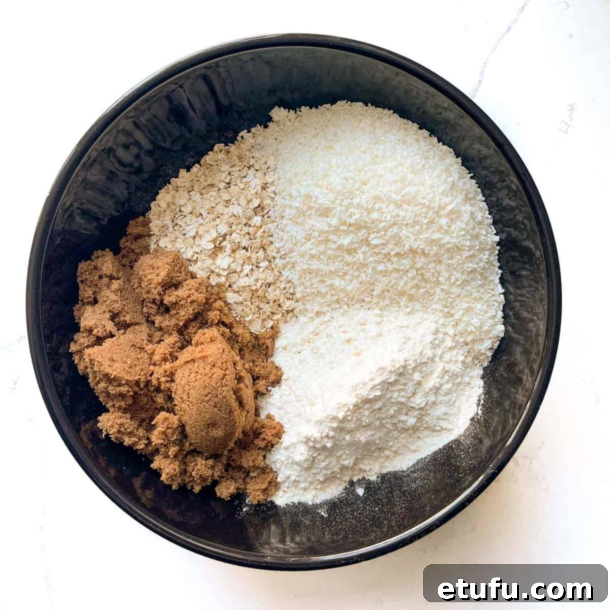 Adding the flour, oats, brown sugar and coconut to a large bowl for the coconut biscuits.