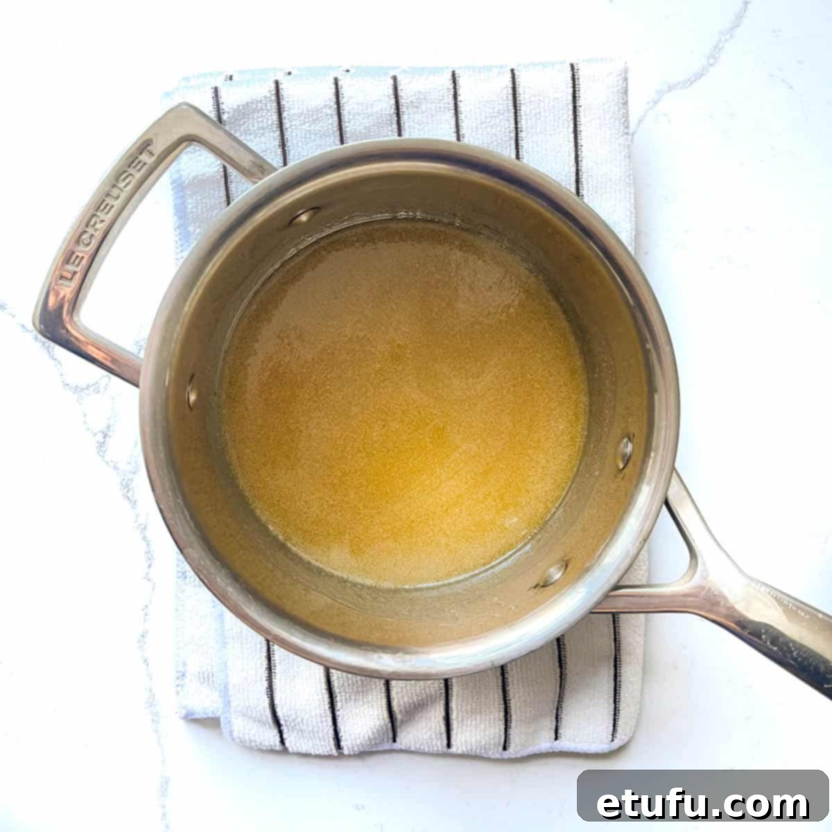 Melted butter in a small saucepan on a white kitchen towel.