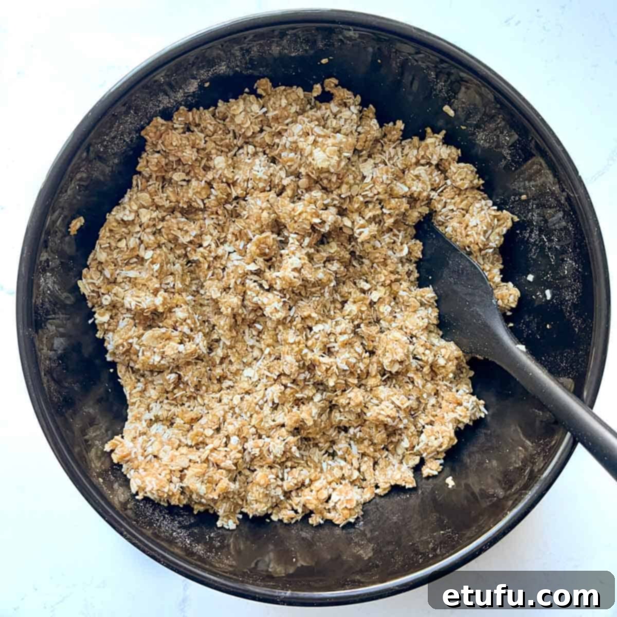 Coconut biscuit cookie dough mixed in a large black bowl.