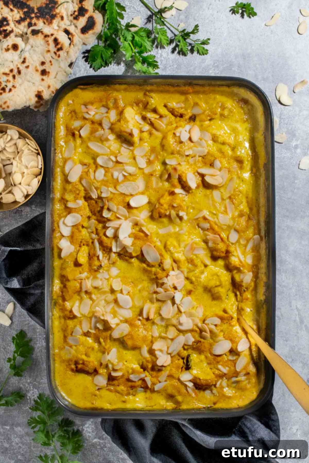 A sumptuous Chicken Pasanda curry, freshly baked, sits invitingly in a black baking dish, promising warmth and flavor.