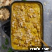 A beautifully presented Pasanda curry in a black baking dish, adorned with flatbread, flaked almonds, and fresh coriander.