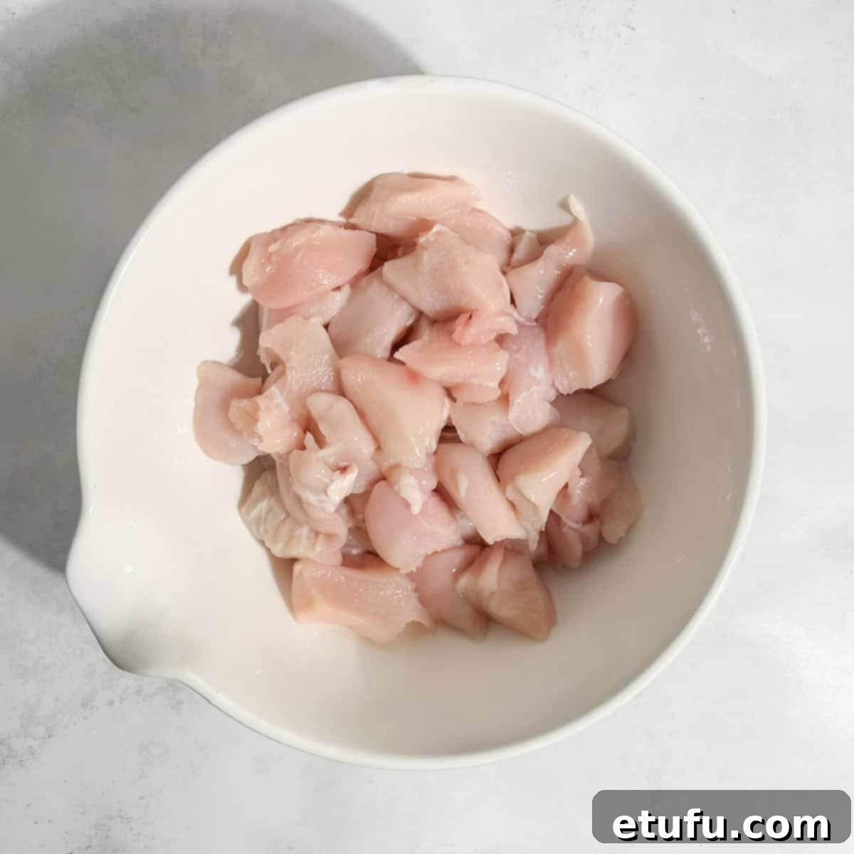 Finely chopped chicken pieces, ready for the Pasanda curry, neatly arranged in a small white bowl.