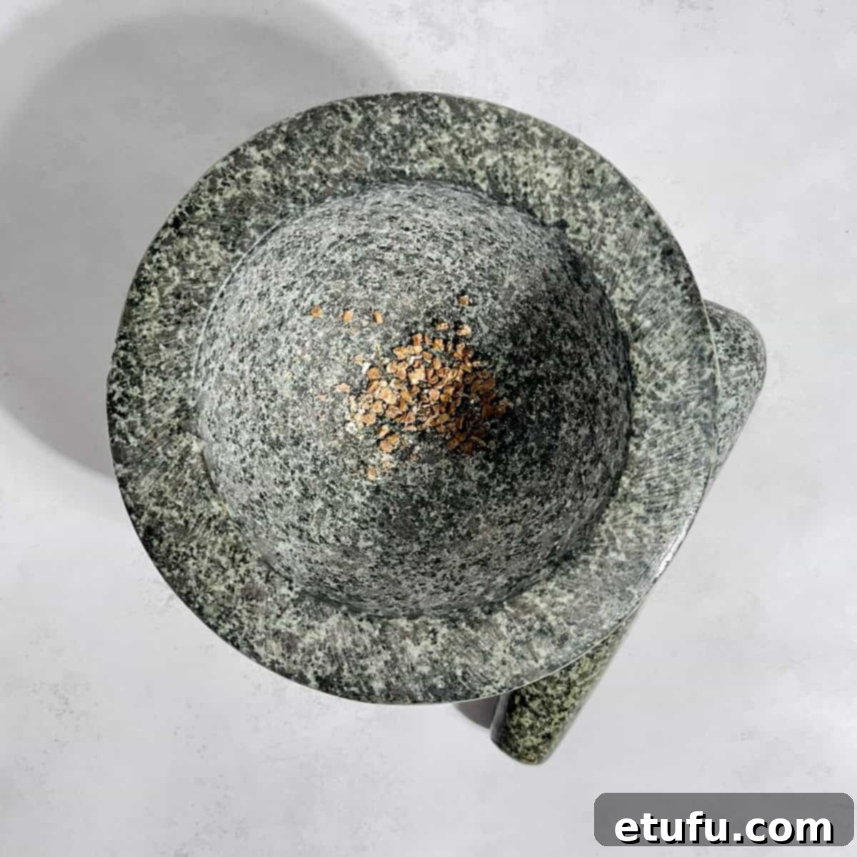 Fragrant cardamom seeds being crushed in a traditional mortar and pestle, releasing their potent aroma.