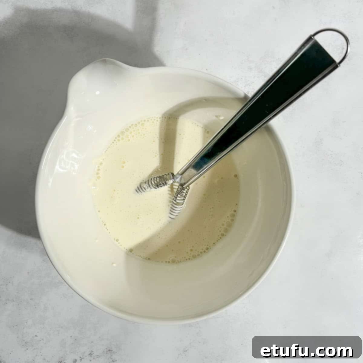 Double cream and cornflour expertly whisked together in a small white bowl, ready to thicken the Pasanda.