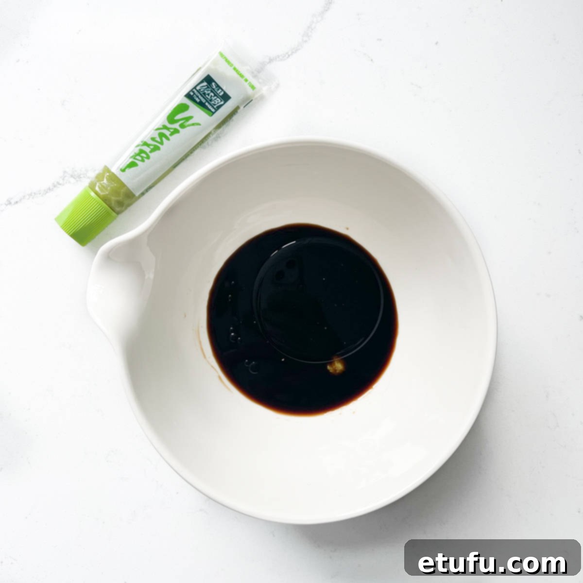 Adding soy sauce to a white bowl for the sushi salad dressing.