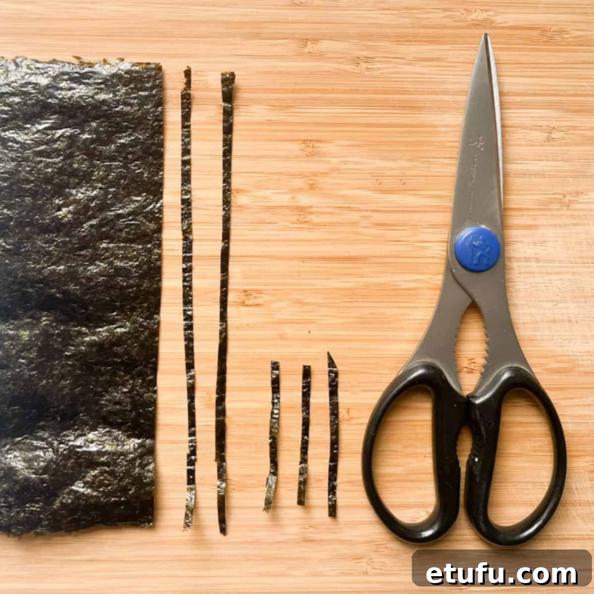 Cutting strips of nori with a pair of kitchen scissors.