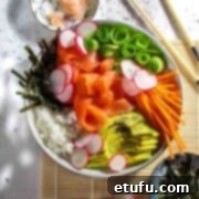 Sushi salad in a white bowl with extra bowl of ginger, salad dressing and nori strips.