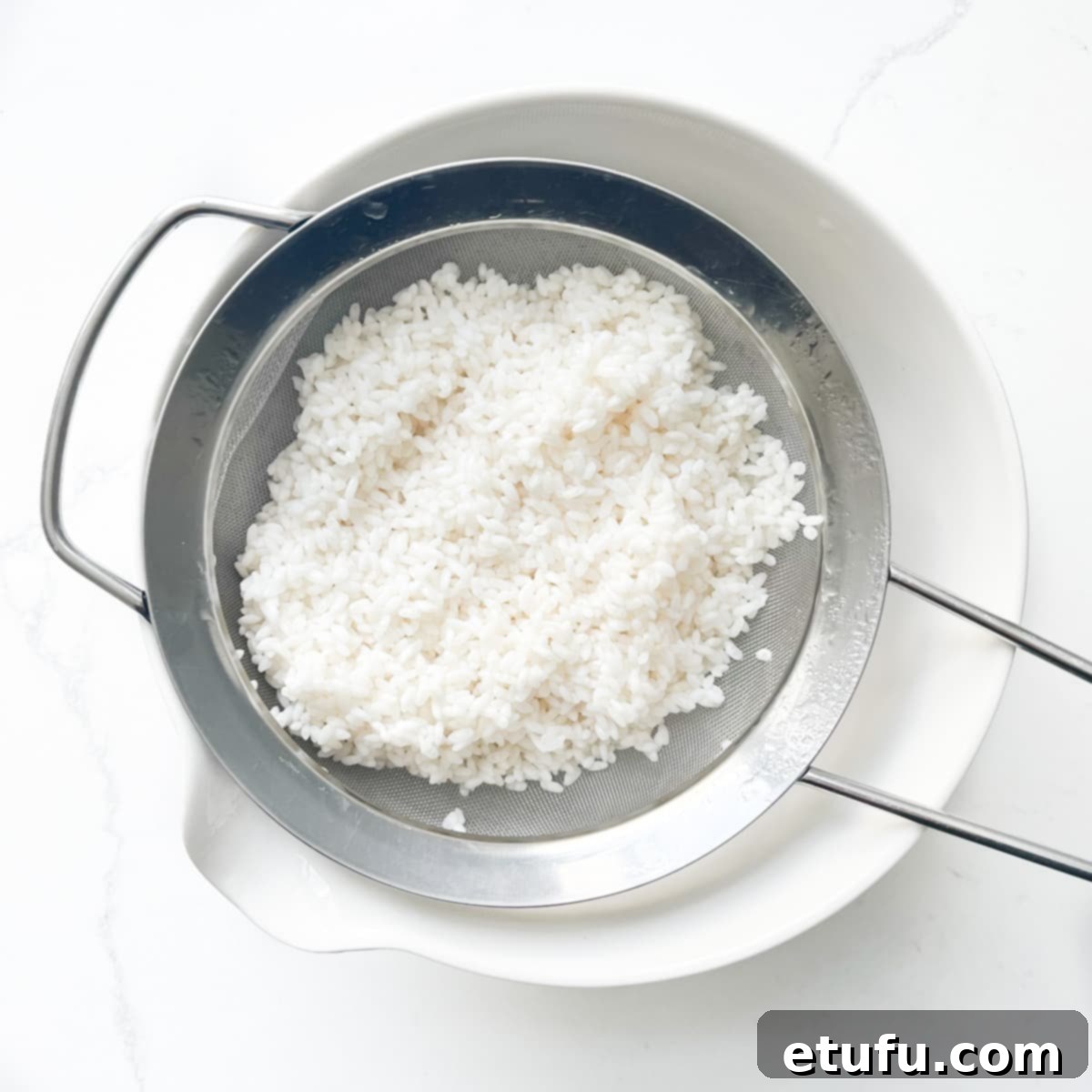 Draining soaked sushi rice.