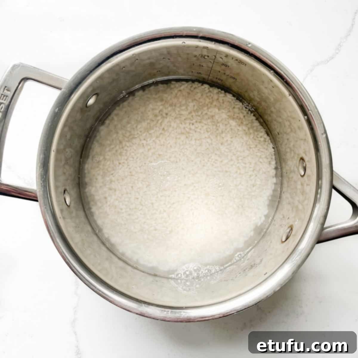 Sushi rice in a saucepan covered with water.