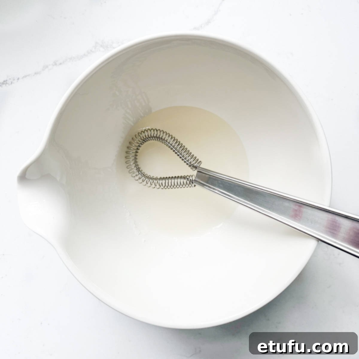 Adding rice vinegar to a white bowl.