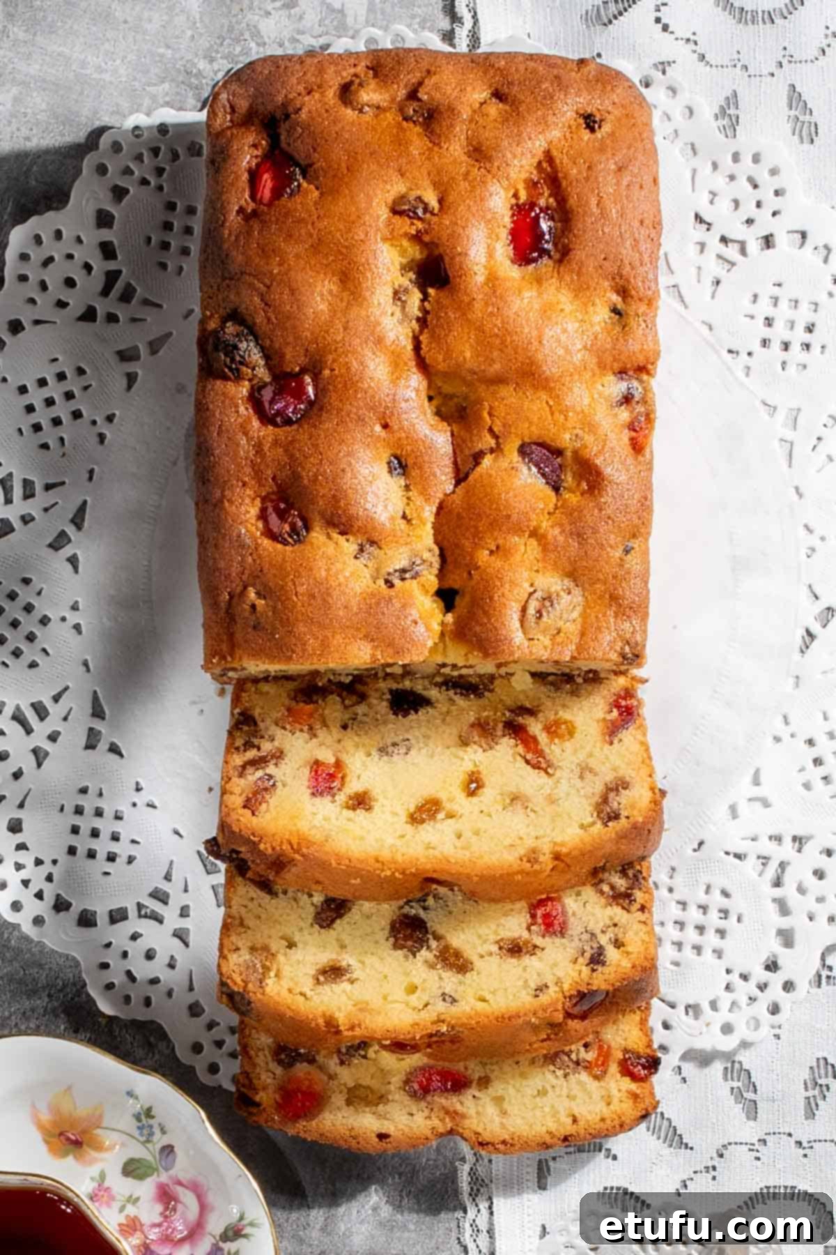 A beautifully sliced sultana cake resting on delicate white doilies, showcasing its moist texture and plump sultanas.