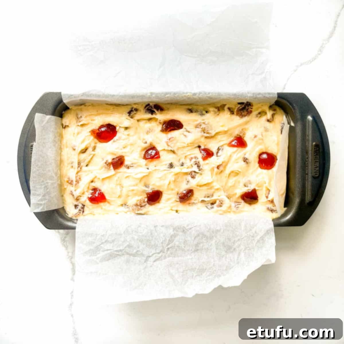 The sultana loaf cake mixture spooned into the prepared loaf tin, ready for baking.