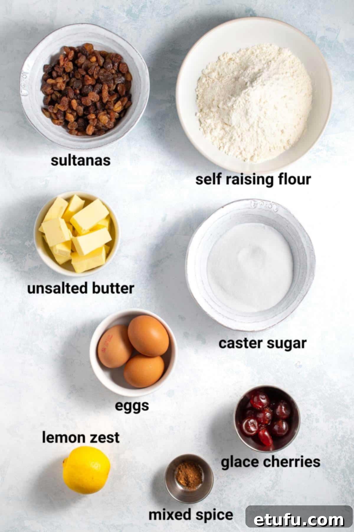 Assorted ingredients for making sultana cake, including butter, sugar, eggs, flour, and a bowl of sultanas.