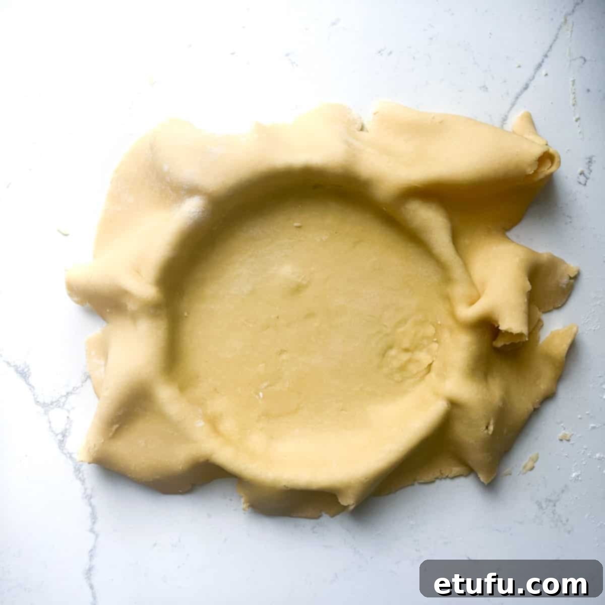 Exquisite French Fruit Tart 16 Pastry dough wrapped over a tart case with excess pastry draping over the sides.