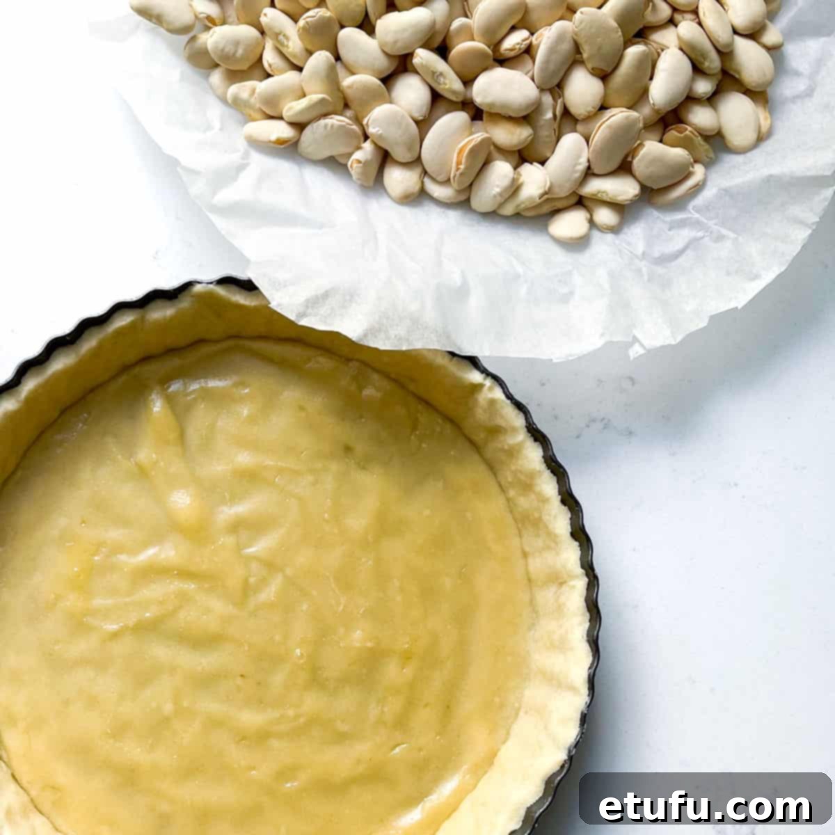 Exquisite French Fruit Tart 22 A half-baked pastry case with the baking beans removed and to the side.
