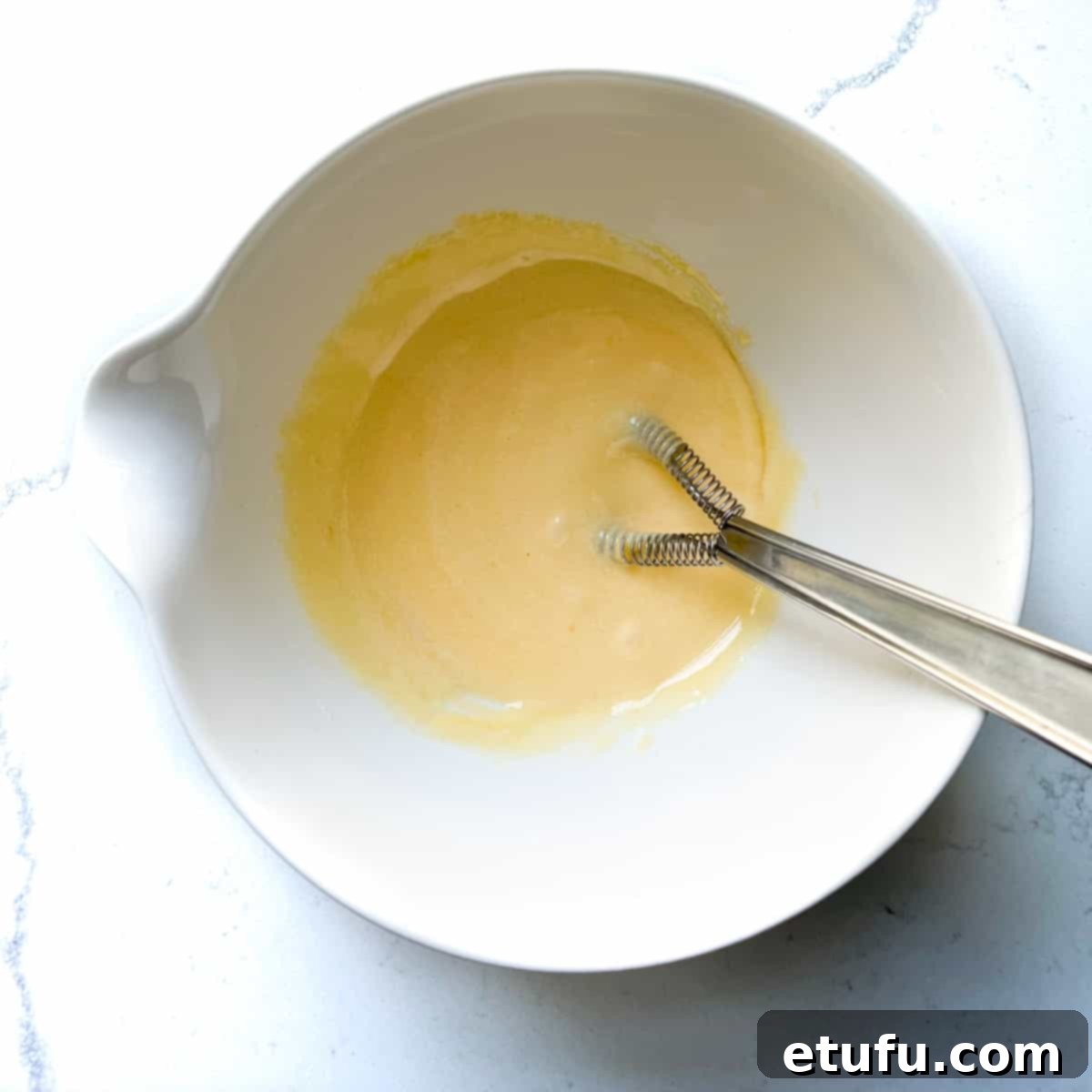 Exquisite French Fruit Tart 26 Whisking egg yolks and sugar in a white mixing bowl.