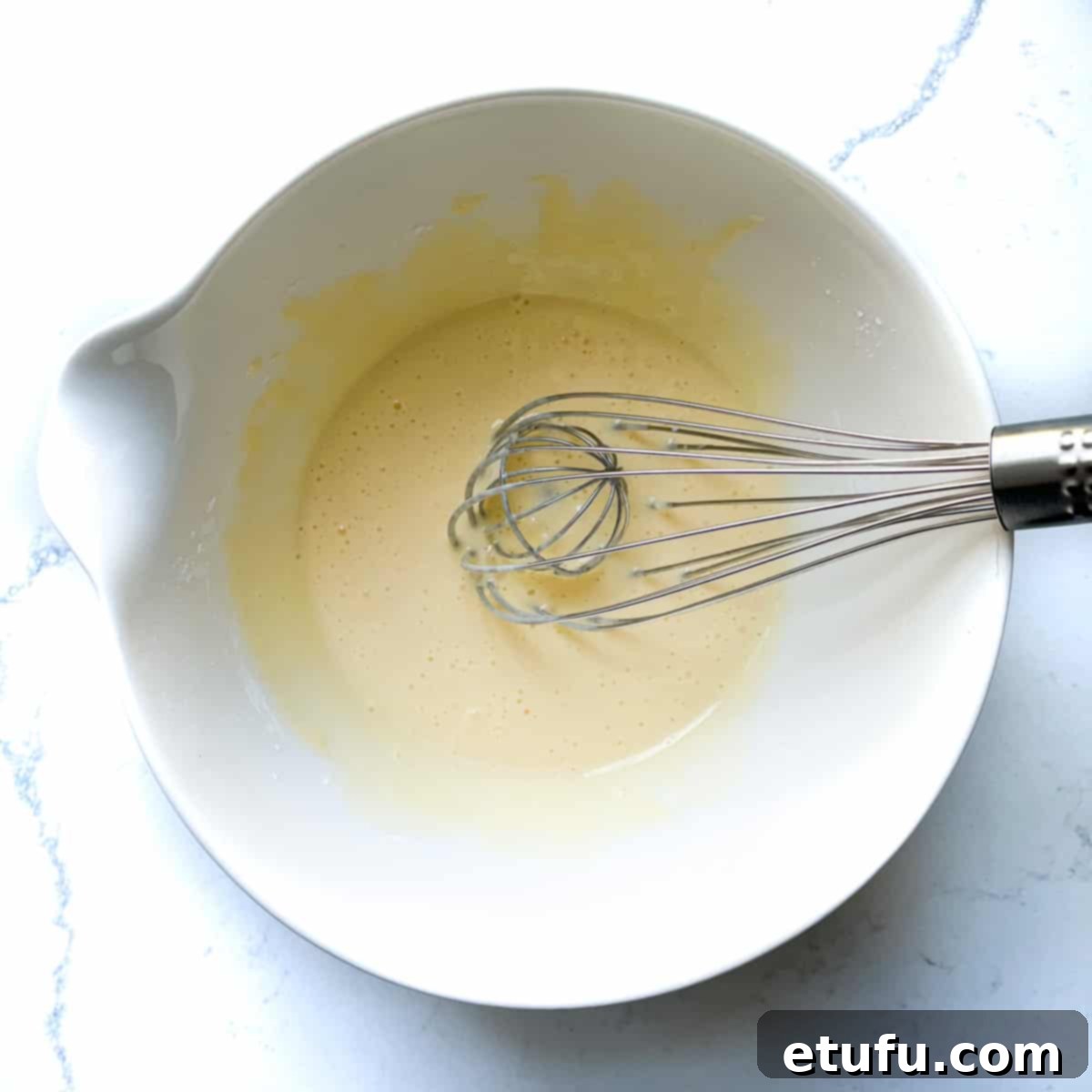 Exquisite French Fruit Tart 28 Whisking cornflour into egg mixture in a white mixing bowl.