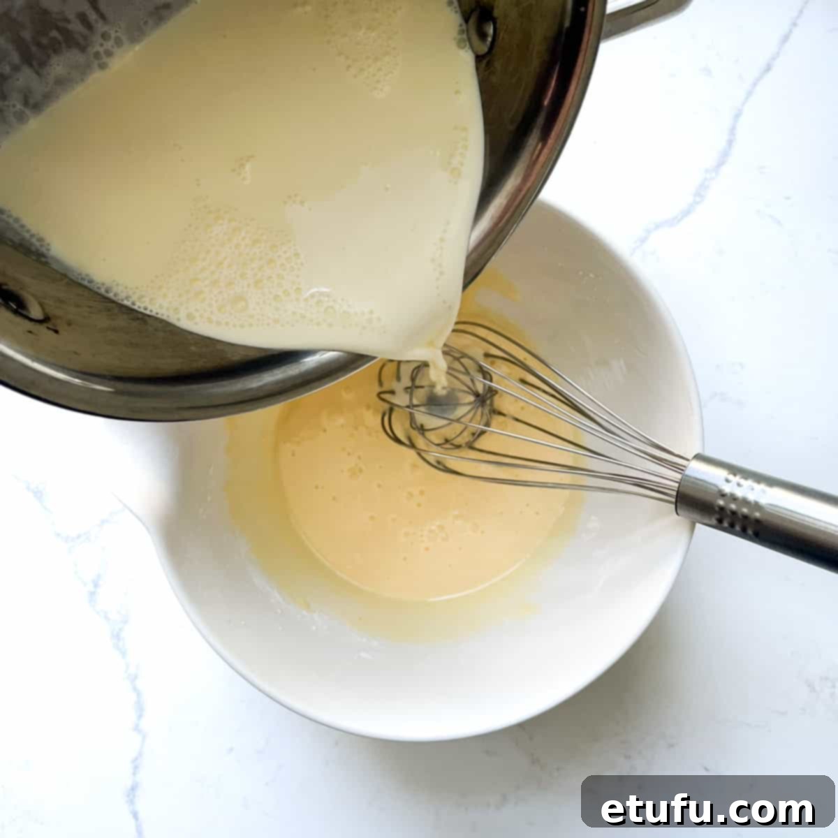 Exquisite French Fruit Tart 30 Pouring a quarter of the milk into the eggs in a large mixing bowl.