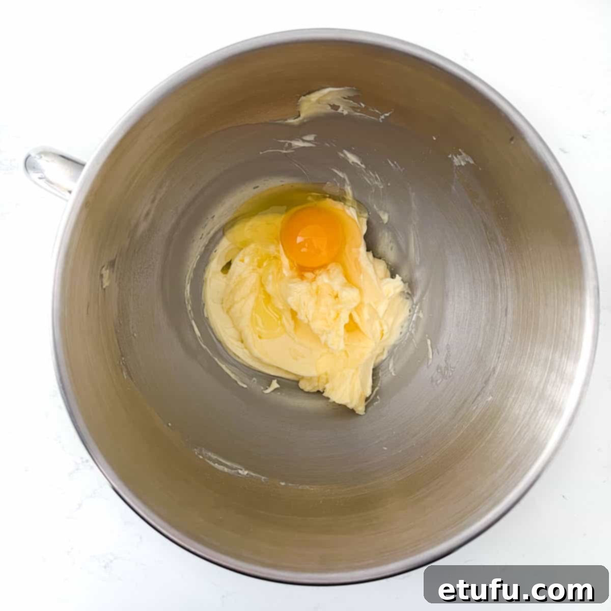 Exquisite French Fruit Tart 8 Adding one egg to the butter mixture in the bowl of a stand mixer.