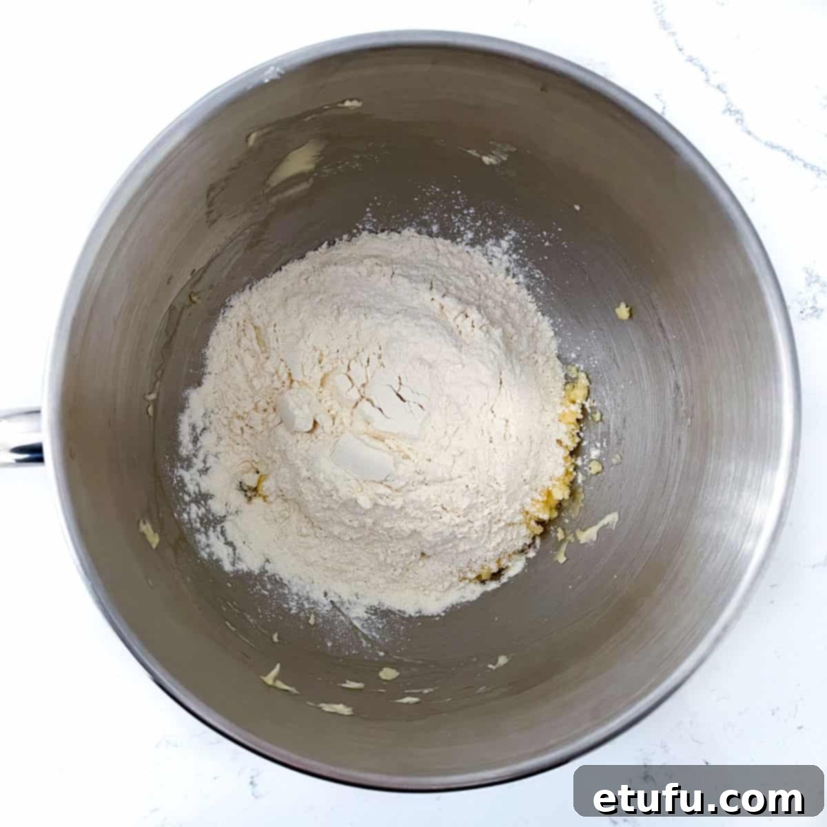 Exquisite French Fruit Tart 9 Adding flour to the eggs and butter in the bowl of a stand mixer.