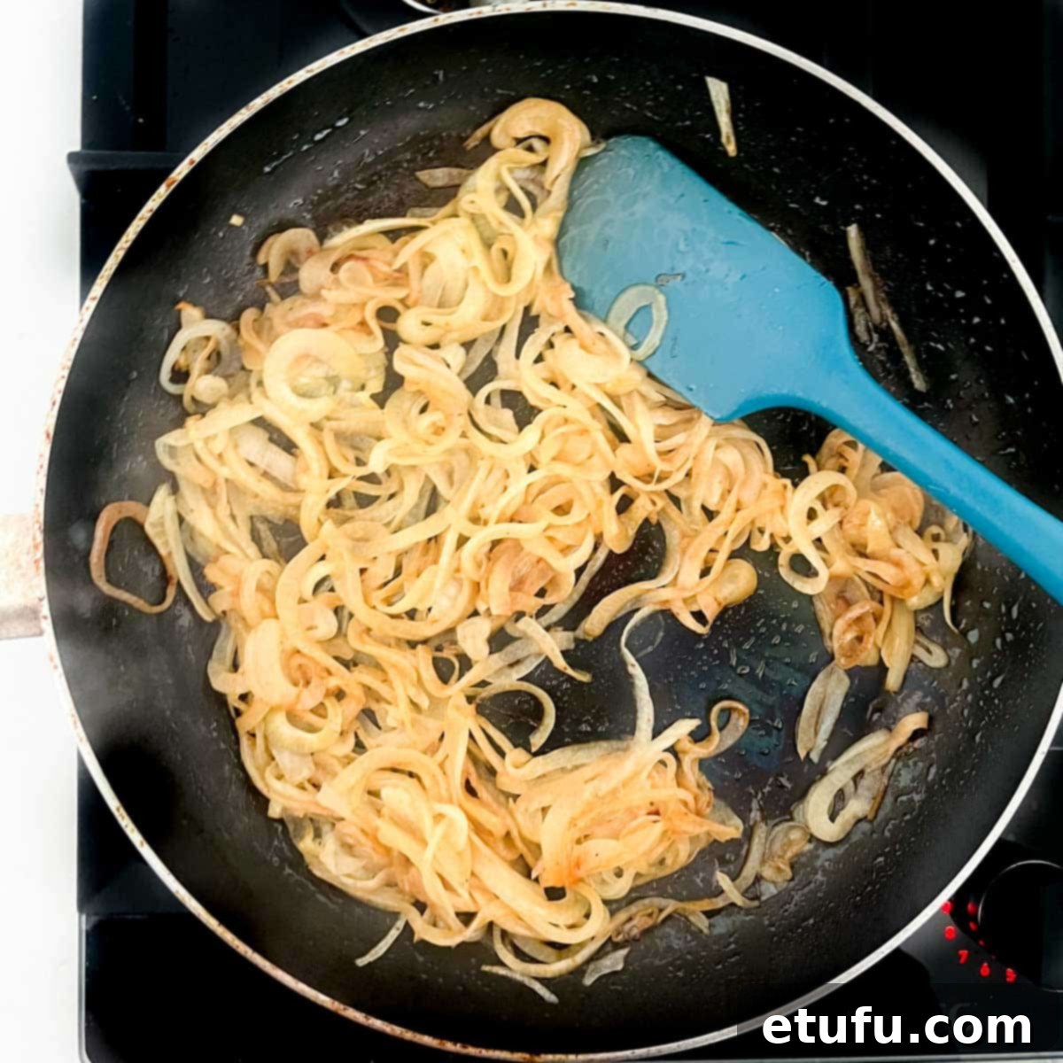 Caramelizing onions in a large frying pan, now golden brown and soft after adding brown sugar, ready for the Flammkuchen.