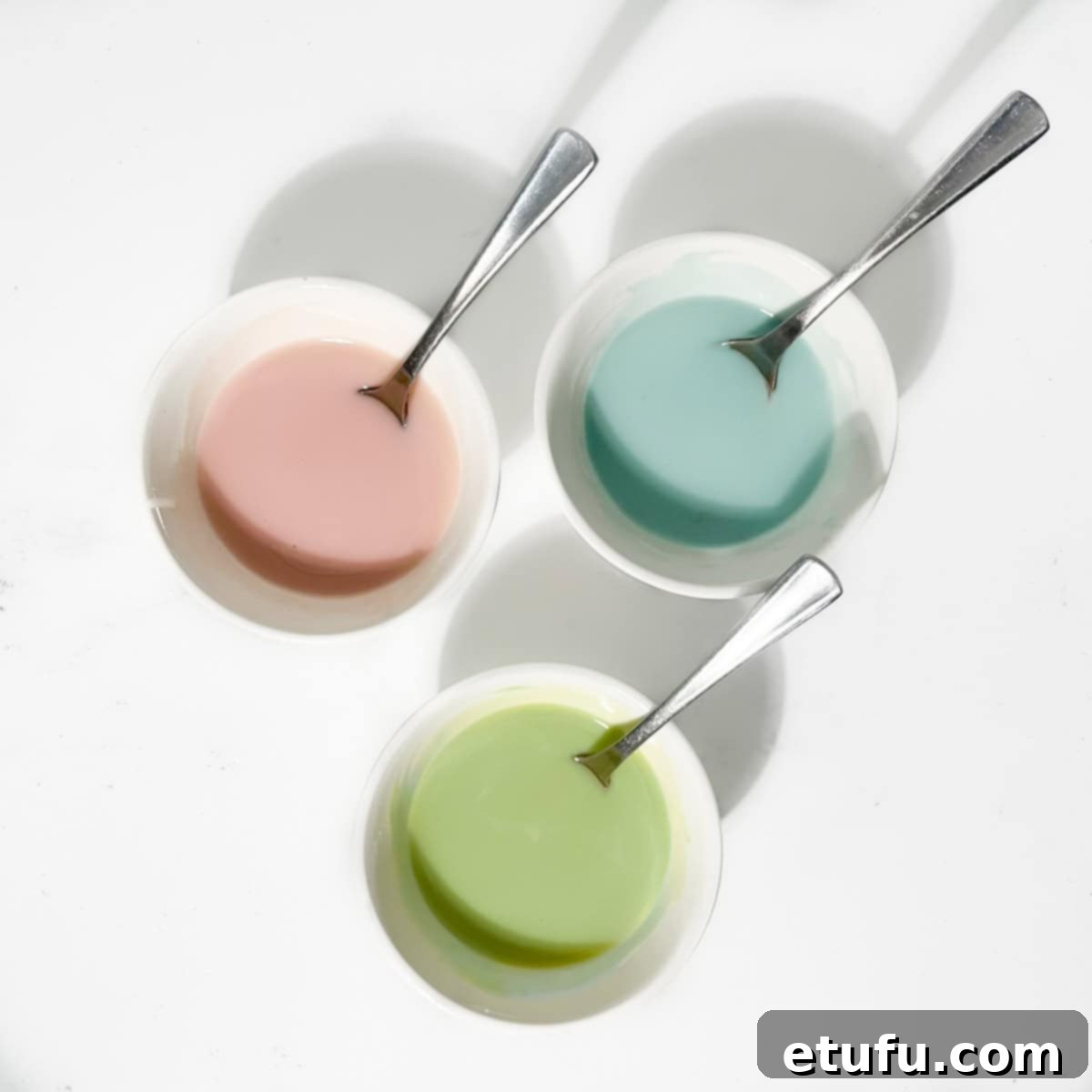 Three small bowls of blue, green and pink icing.