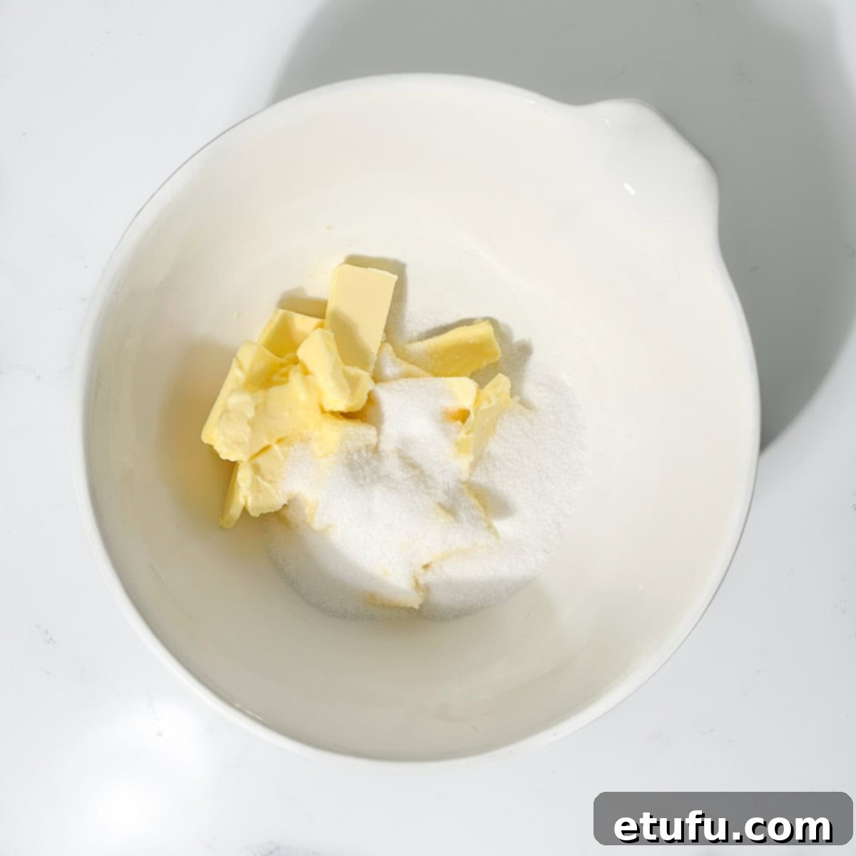 Adding butter and sugar to a large white bowl.