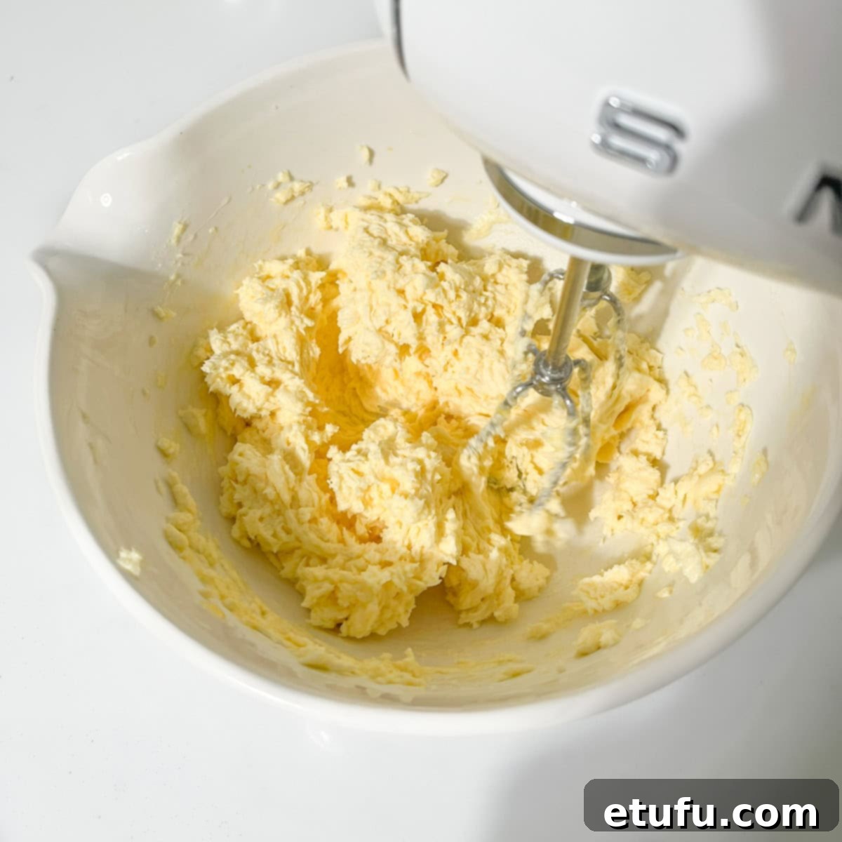 Beating the egg into the butter and sugar mixture with an electric hand mixer.