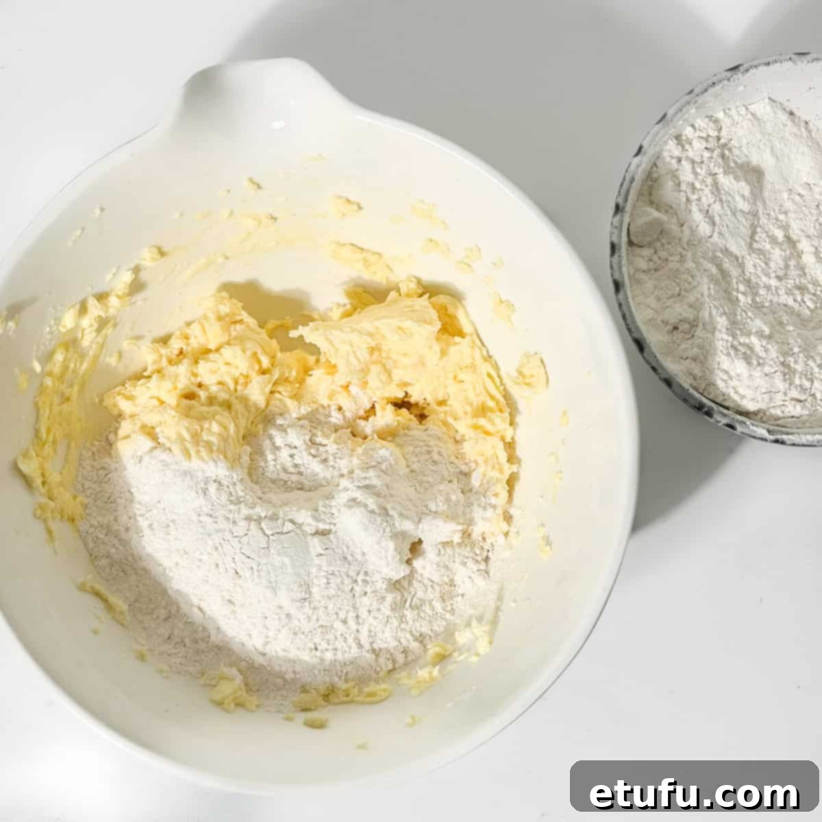 Adding flour to the bowl of thumbprint icing cookie dough.