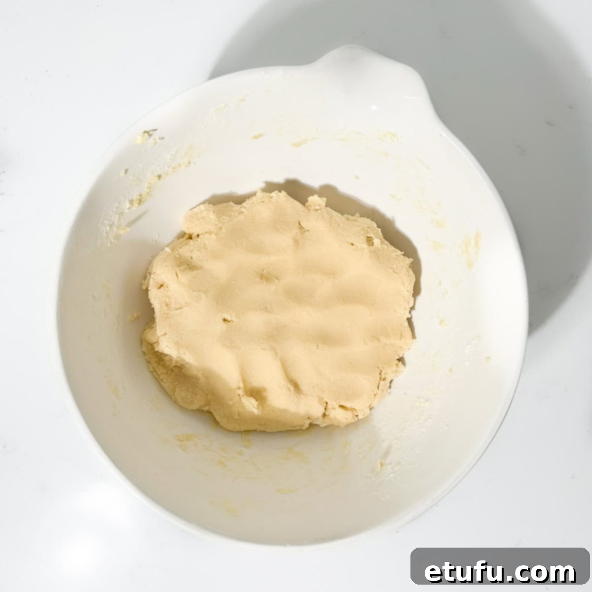 Cookie dough for the thumbprint cookies with icing in a large white bowl.