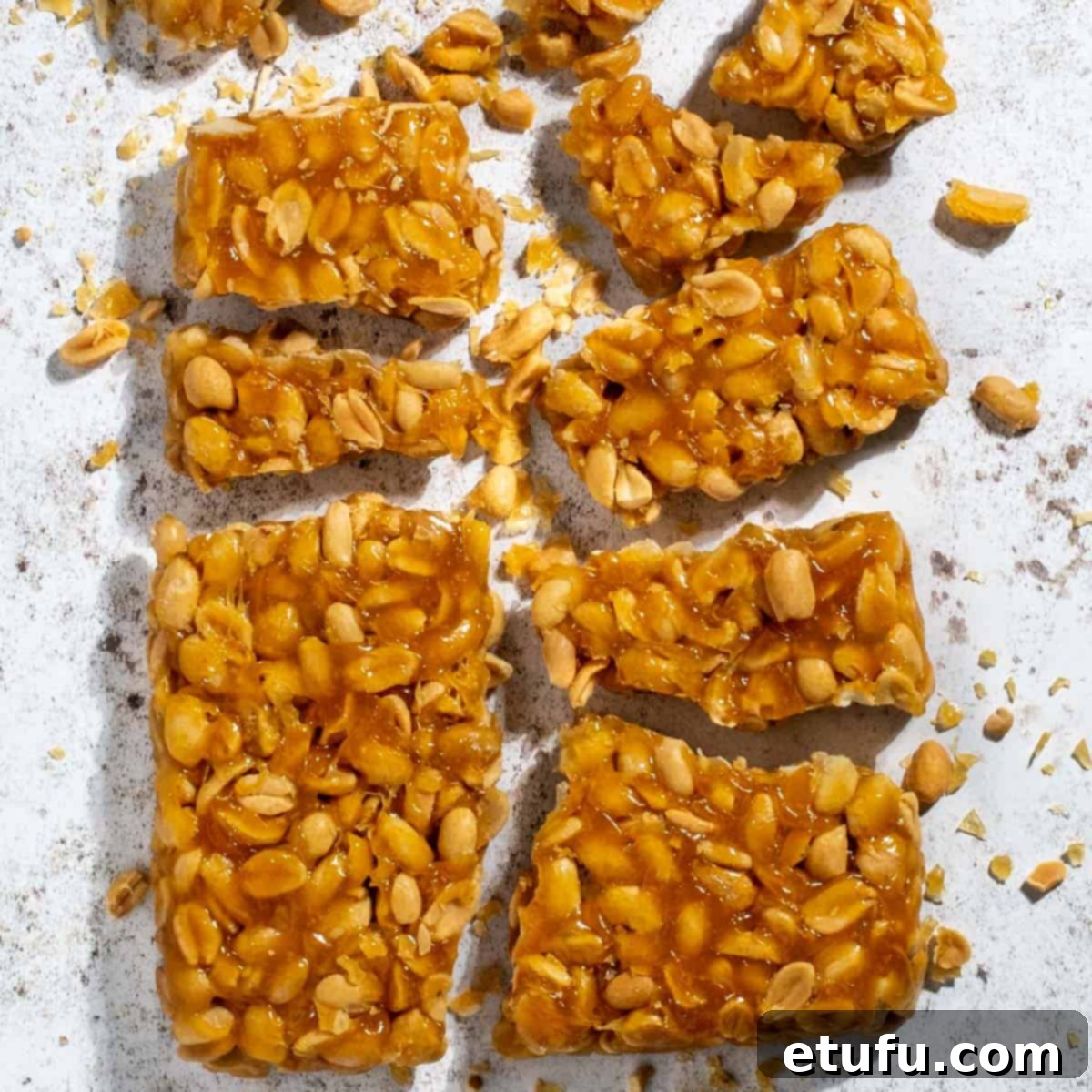 Beautifully broken pieces of homemade peanut brittle without corn syrup, showcasing its perfect texture and golden hue, presented on a clean white background.