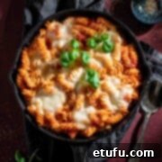Pasta alla sorrentina in a cast iron frying pan resting on a grey napkin.