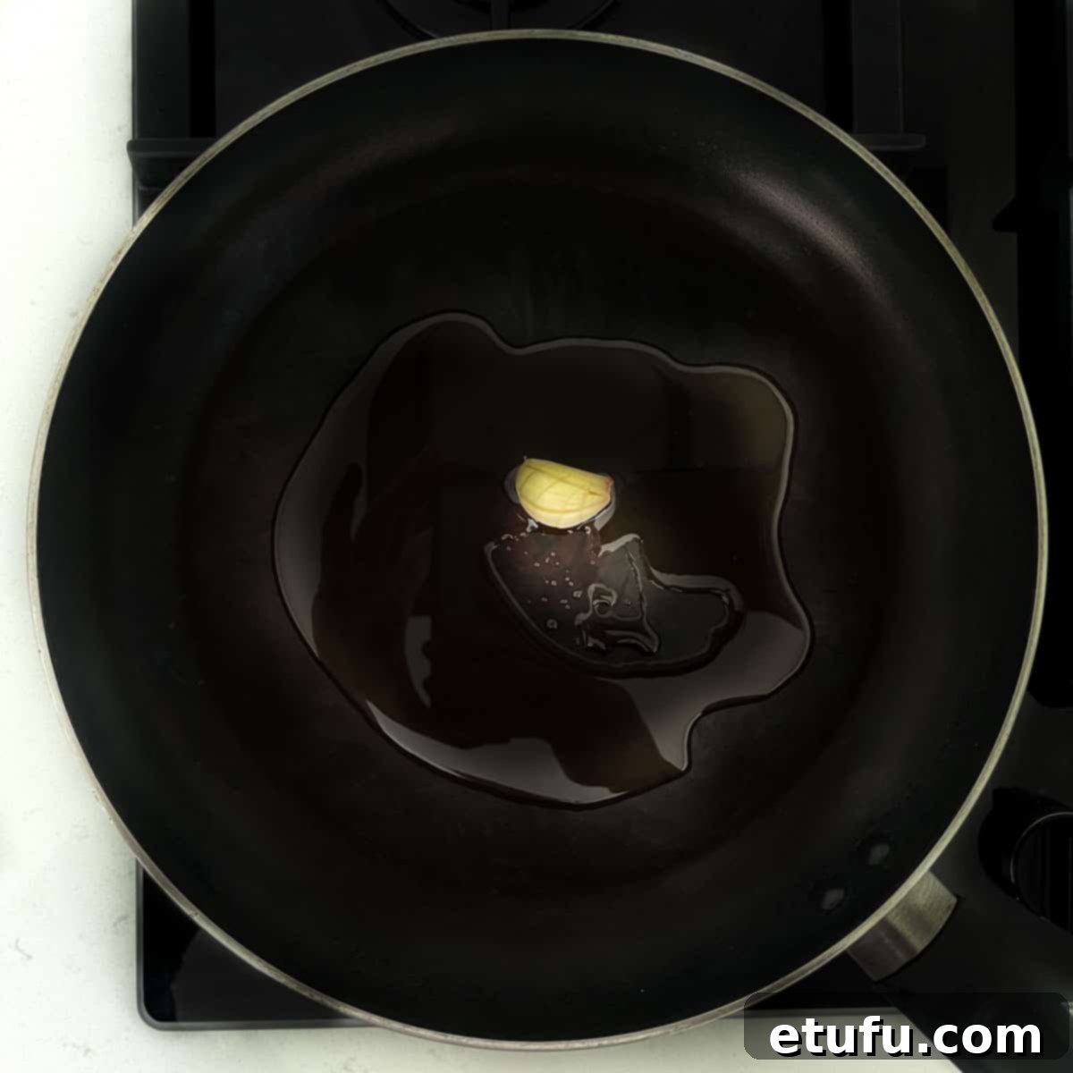 Frying a garlic clove in olive oil in a frying pan.