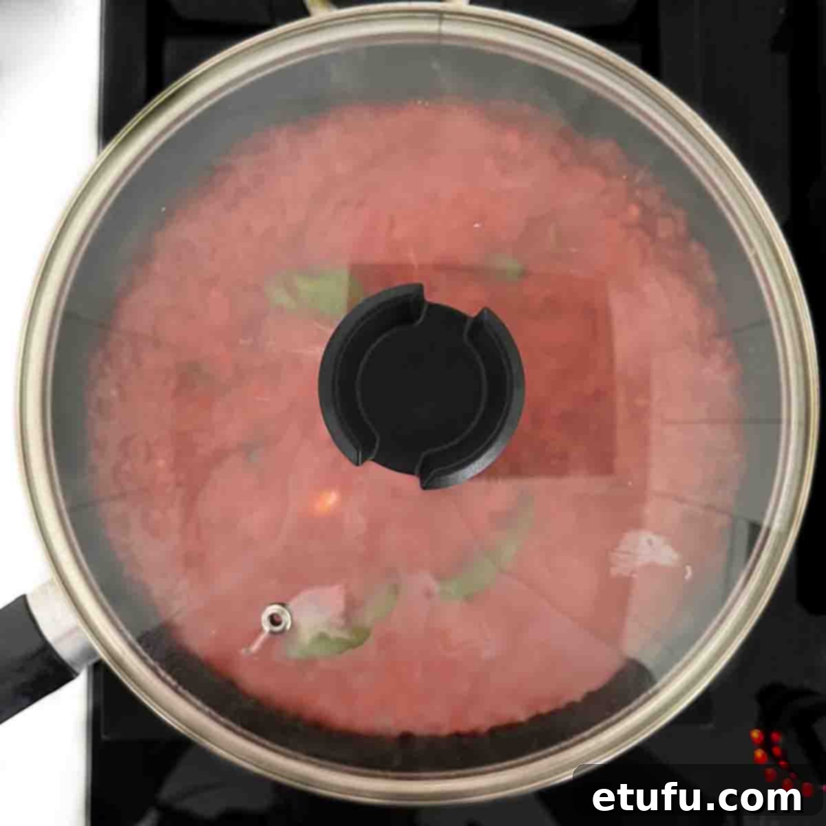 The sauce for Pasta all Sorrentina cooking in a lidded frying pan.