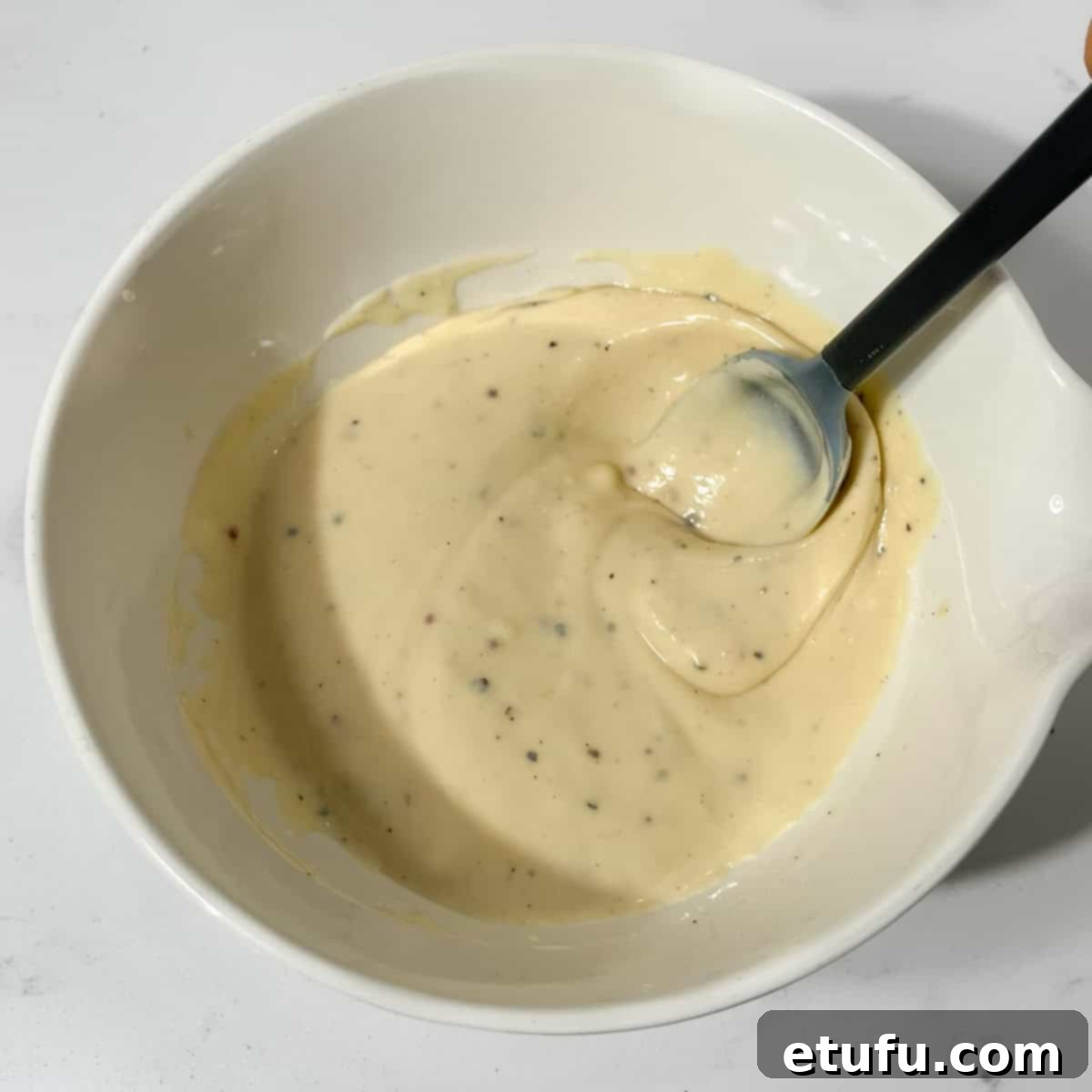 Salad dressing for the creamy italian pasta salad in a small white bowl.