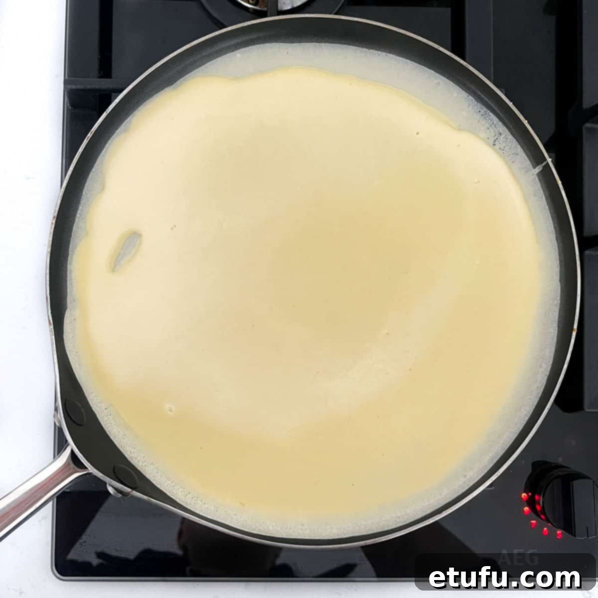 Pandekager batter poured into a pancake pan.