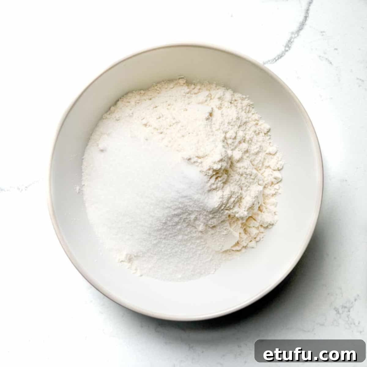 Adding the dry ingredients to a white bowl. 