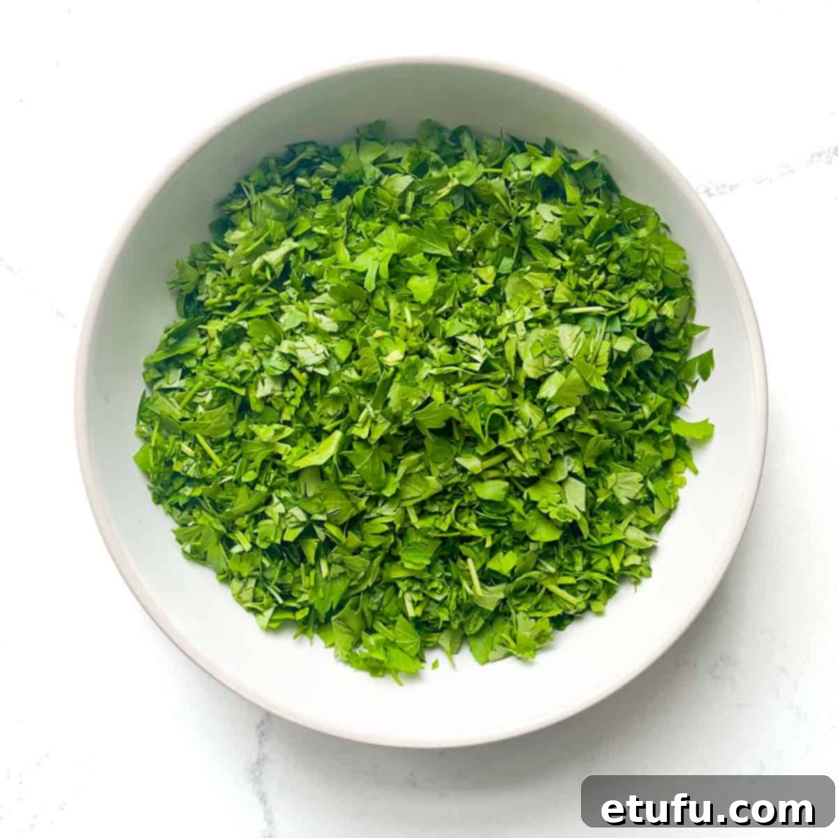 Chopped parsley for the Taboule in a white bowl.