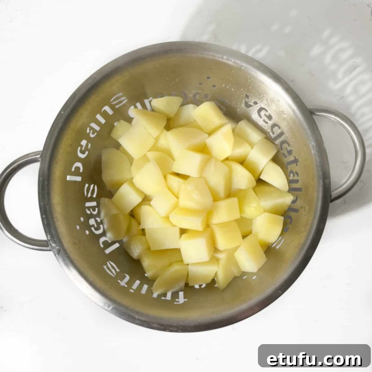 Potato cubes draining in a colander.