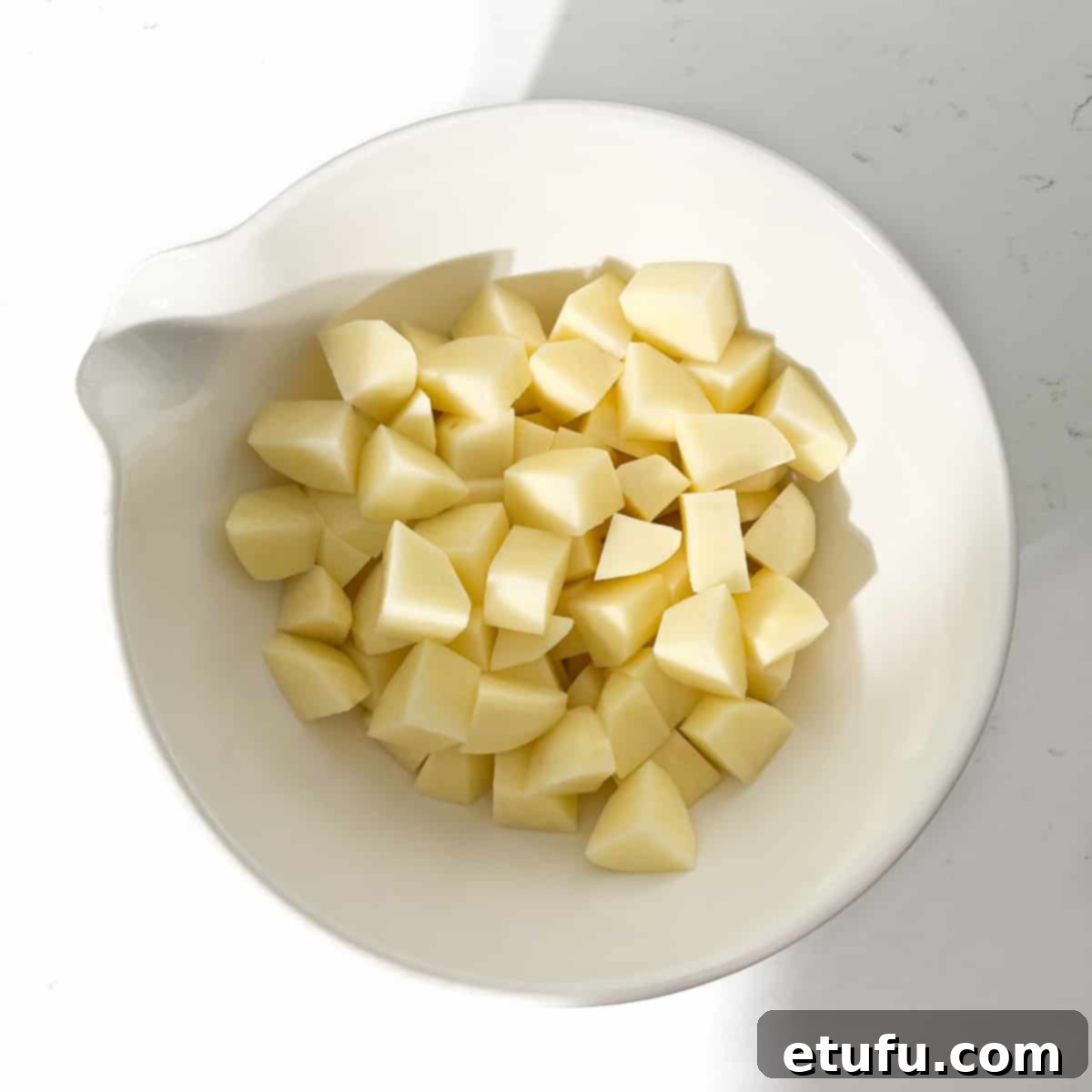 Potato cubes in a large white bowl.