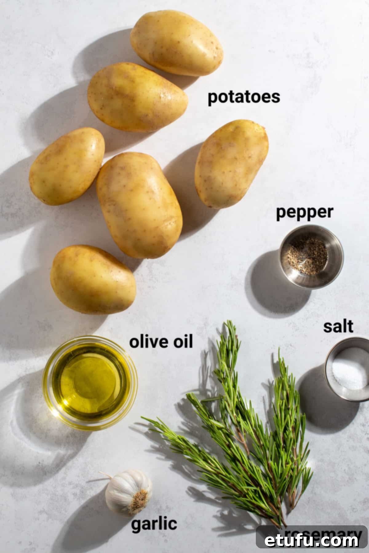 Selection of ingredients for Parmentier Potatoes including potatoes, oil, rosemary, and garlic.