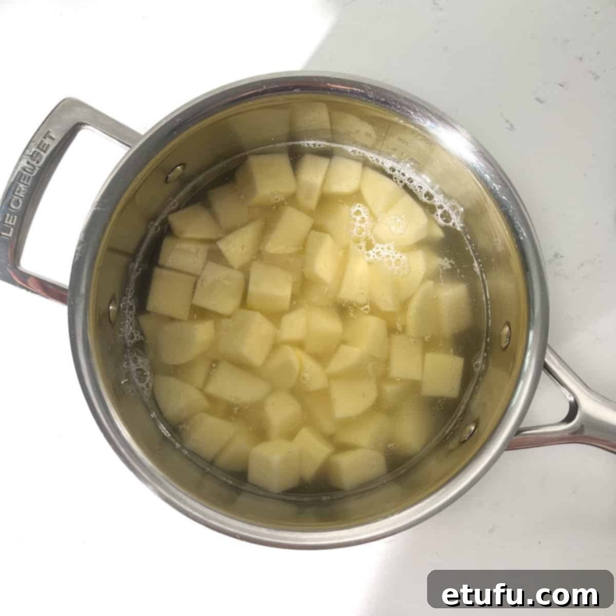 Potato cubes for parmentier potatoes in a large saucepan, covered with water.
