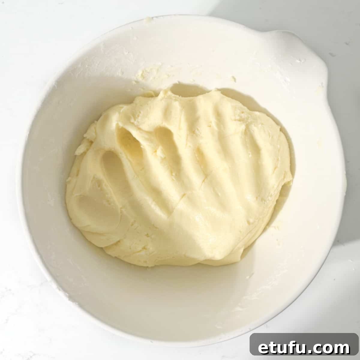 Mixed sequilho dough ready for rolling in a large white bowl.