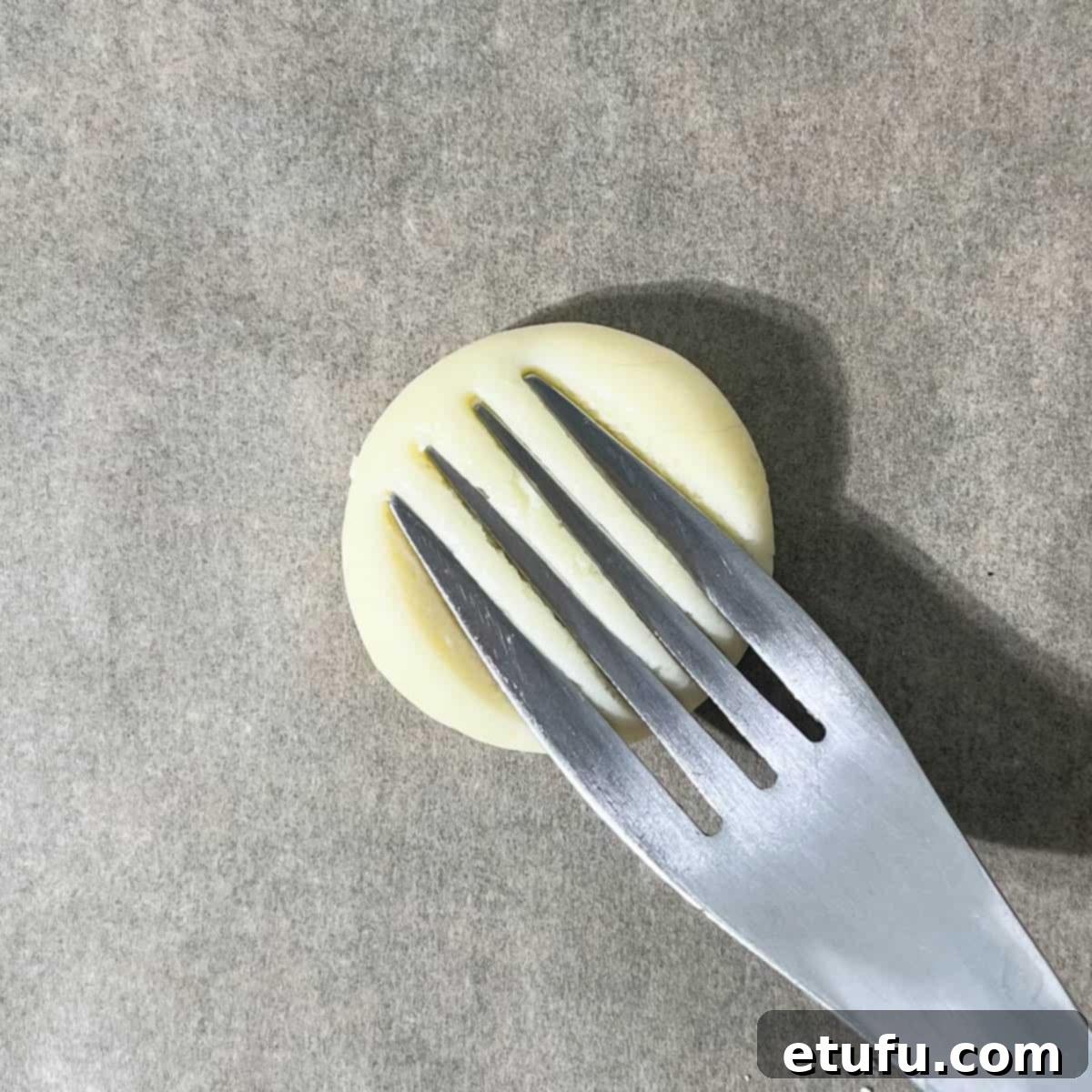 Flattening a dough ball with a fork.