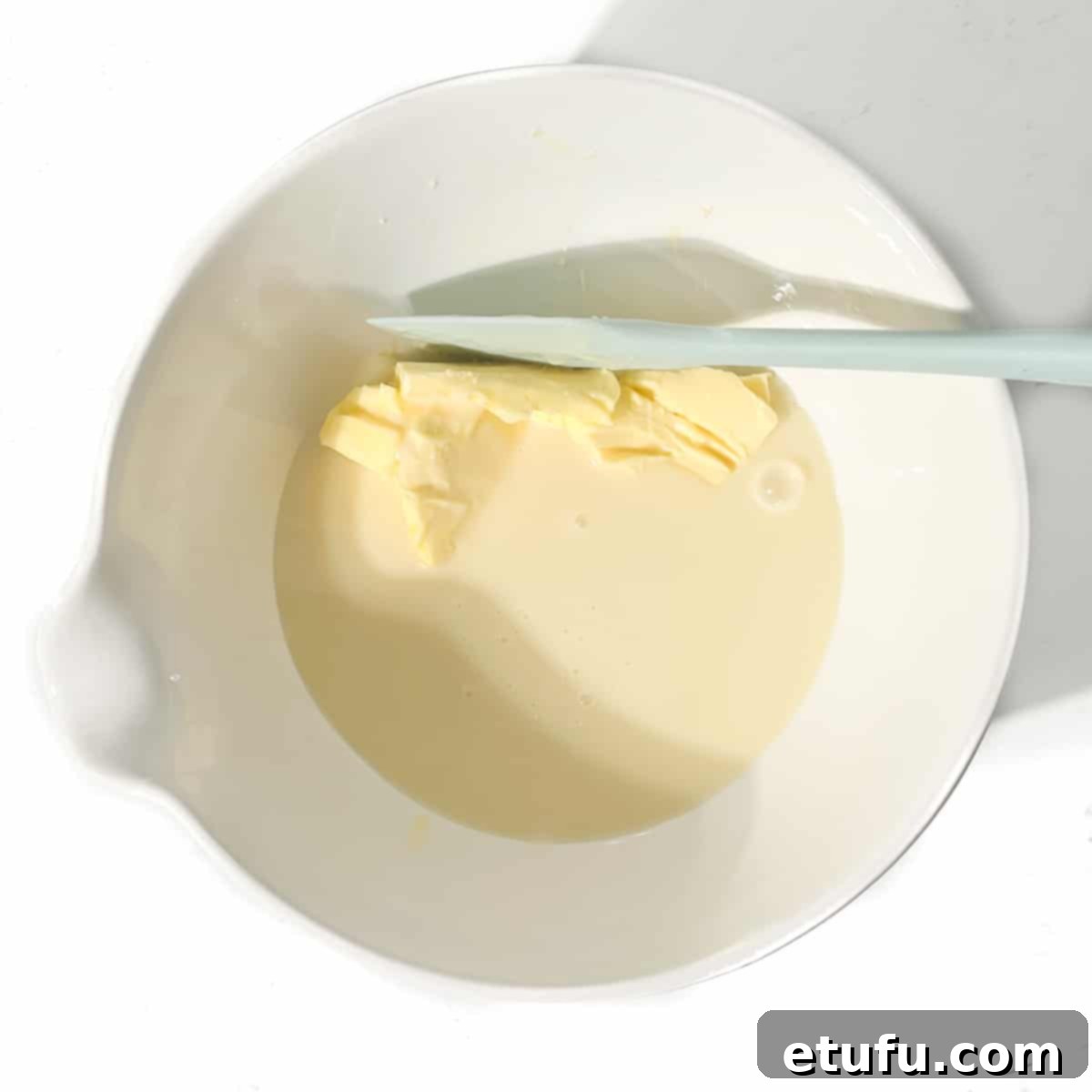 Adding condensed milk and butter to a large white bowl.