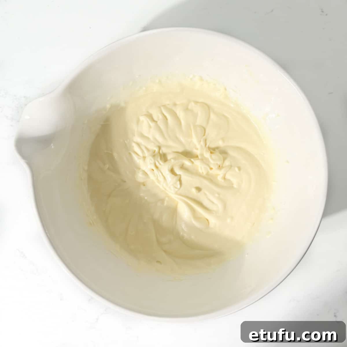Mixed condensed milk and butter in a large white bowl.