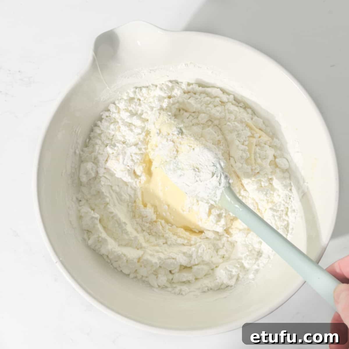 Folding cornflour into the butter and condensed milk for sequilho dough.