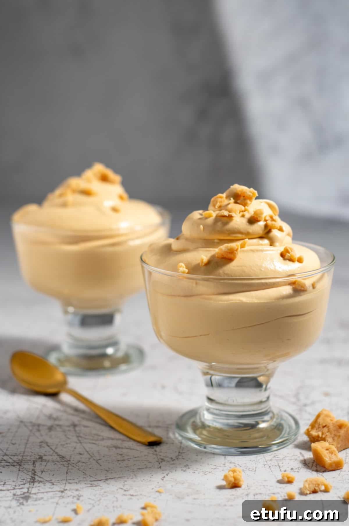 Two portions of dulce de leche mousse in elegant parfait glasses, garnished lightly.