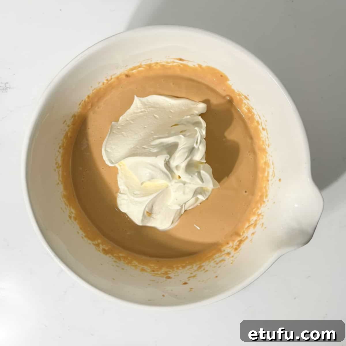 Adding the freshly whipped cream to the dulce de leche and cream cheese mixture.