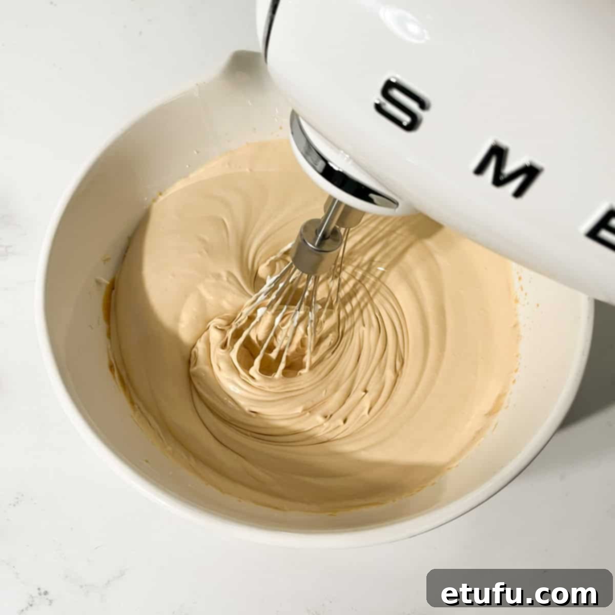 Whipping the combined dulce de leche mousse mixture until it thickens and forms soft trails.